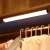 White motion sensor LED light bar installed in a closet, illuminating the hanging clothes