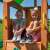 Woodlit Somerset playset tower with two children sitting on the platform