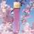 Michael Kors Sexy Blossom Eau de Parfum Spray, 100 ml, rózsaszín üveg arany kupakkal, rózsaszín virágok hátterében