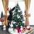Woman decorating a Springos 120 cm diamond fir artificial Christmas tree with white decorations