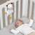 Baby looking at Fehn musical zebra toy in crib