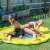 Two kids playing in the yellow 170cm diameter splash mat with blue and red fish design