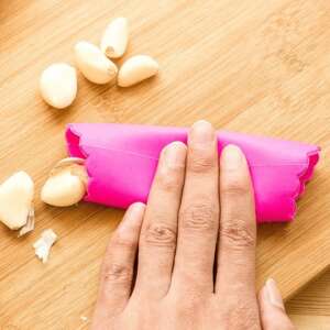 Hand using a pink silicone garlic peeler to peel garlic cloves - Peeler