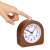 Close-up of the Navaris analog wooden alarm clock with a finger pressing the light button