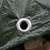 Close-up of a metal eyelet on a green waterproof tarpaulin