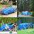 Waterproof blue tarp covering car, woodpile, tent, and construction materials.