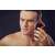 Man using Eldom electric shaver, black and orange, 3 blades, close-up