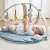 Baby playing with Nattou Felix and Leo wooden play gym with blue play mat and hanging toys