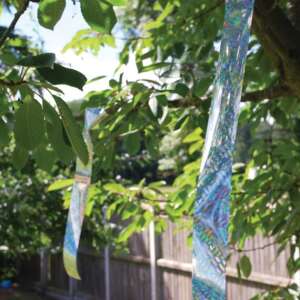 Bird repellent tape hanging on a tree branch, reflecting light - Bird control
