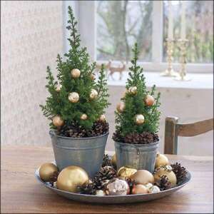 Karácsonyi asztali dísz két kis díszített karácsonyfával cserépben, fenyőtoboz és arany díszek veszik körül - Ambiente