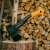 Fiskars X14 XS Camping-Axt auf einem Holzscheit mit einem Stapel Brennholz im Hintergrund