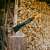 Fiskars X24 S Spaltaxt auf einem Holzscheit mit Holzstapel im Hintergrund