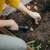Woman using Fiskars Solid™ Planting Trowel, Black, to plant bulbs in a garden bed