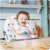 Baby sitting in Ricokids ELDO high chair, white and grey with stars