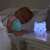 Luna the Calming Kitty night light on a bedside table, with a child sleeping in the background