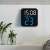 Digital LED alarm clock with blue display mounted on a wall