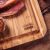 Close-up of Tramontina Churrasco logo on teak cutting board with steak