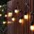 Kertészeti Branda 10 LED E27 10m string lights with warm white bulbs, hanging on a fence