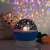Star projector night light projecting on a wall with a teddy bear and a rose