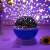 Star projector night light projecting on a wall with purple and blue stars