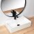 Angled view of Rea Valeria N rectangular bathroom sink with black faucet and round mirror