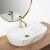 Rea Aura oval marble washbasin with gold faucet and mirror in bathroom setting