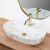 Rea Aura oval marble washbasin with gold faucet and mirror on wooden countertop