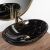 Pamela black marble effect oval washbasin with gold faucet and mirror reflection