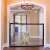 Magic Gate adjustable mesh pet gate for dogs, showing a dog sitting behind the gate in a hallway