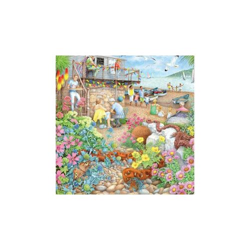 Puzzle Ravensburger Beach Garden Cafe 1000 dielikov zobrazujúce živú plážovú scénu s kaviarňou, kvetmi a ľuďmi užívajúcimi si more.
