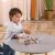 Child playing with Viga PolarB wooden shape sorting clock and bead string.