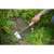 Person using a stainless steel weeding hoe with wooden handle to remove weeds from a garden