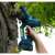 Dedra 18V cordless chainsaw in use, cutting a tree branch, 10cm, 4 inch, blue, electric, pruning saw, branch cutter, tree trimming, garden tool
