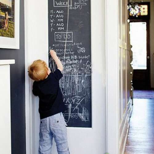 Child using a black chalkboard sticker on a door
