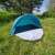 Pop-up beach tent, blue and white, set up in a grassy field