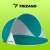 Trizand pop-up beach tent, teal and white, set up on a green background