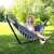 Woman relaxing in a Springos double hammock with a stand, in a garden setting