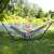 Back view of a woman relaxing in a Springos double hammock with a stand, in a garden setting