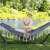 Back view of a woman relaxing in a Springos double hammock with a stand, in a garden setting