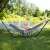Back view of a woman relaxing in a Springos double hammock with a stand, in a garden setting