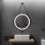 Round LED bathroom mirror with black aluminum frame and eco-leather strap hanging above a bathroom sink