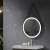 Round LED bathroom mirror with black aluminum frame and eco-leather strap hanging above a bathroom sink