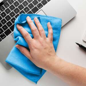 Hand using a blue microfiber cleaning cloth to clean a laptop keyboard - Microfiber cloth