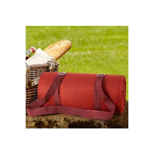 Harmony bordó piknik takaró feltekerve, hordozópántokkal, egy piknikkosár mellett