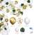White, gold, and clear balloons, green leaves, and confetti for party decorations