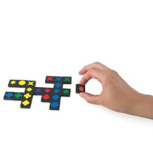 Игра на Qwirkle Пътуваща версия на настолната игра, ръка поставяща плочка на дъската, показваща цветните плочки и форми - Логическа игра