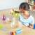 Дете играе с комплекта инструменти за фина моторика Learning Resources Sand & Water, черпейки цветни бонбони от купа