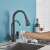 Blackswan M262 kitchen faucet with pull-down sprayer and filtered water spout, matte black, pouring water into a glass