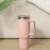 Pink 1200 ml stainless steel travel mug with handle and straw on a wooden surface