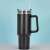 Black 1200ml stainless steel travel mug with handle and lid, on a white table